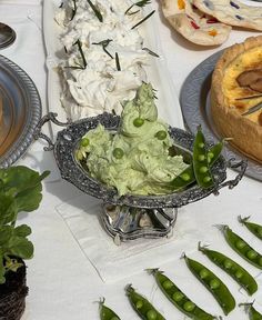 there are many different types of food on the table with plates and spoons next to each other