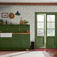 a kitchen with green cabinets and wallpaper in the background, along with a rug on the floor