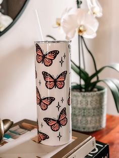 a white vase with pink and black butterflies on it sitting on top of a table