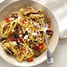 a white bowl filled with pasta, mushrooms and fettuccine next to a fork