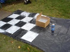 a cardboard box sitting on top of a black and white checkered tarp next to a can