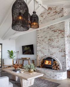 a living room filled with furniture and a fire place next to a brick wall covered in hanging lights