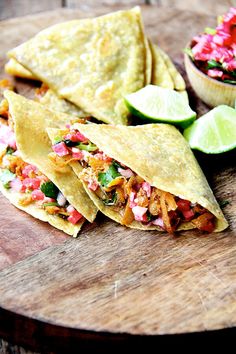 three tortillas on a cutting board with salsa and limes