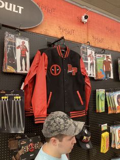 a man is looking at items on display in a store, including jackets and hats