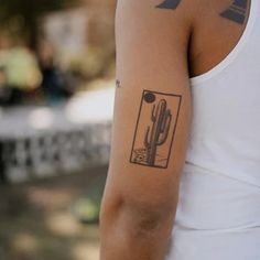 a man with a cactus tattoo on his left arm and right arm behind him is a white tank top