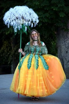 a woman in a costume is holding a large dandelion