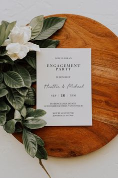 a wooden cutting board topped with white flowers and greenery next to a card that says nothing fancy just love