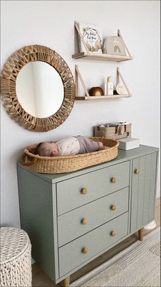 a baby sleeping in a crib next to a wall mounted mirror and shelf above it