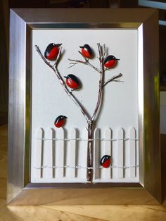 three red and black birds sitting on top of a tree in front of a white fence