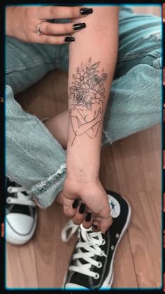 a woman's arm with a tattoo on it and flowers in the middle of her arm