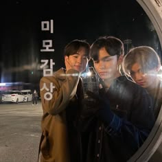 three young men standing next to each other in front of a round window with korean characters on it