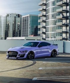 a purple car is parked in front of some tall buildings