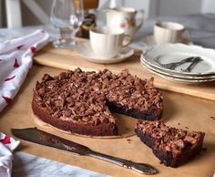 a chocolate cake on a cutting board with two slices cut out and plates in the background