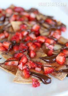 chocolate sauce drizzled over strawberries on top of waffles that are sitting on a white plate