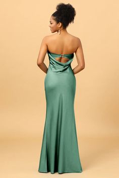 a woman in a long green dress with her back to the camera, looking down