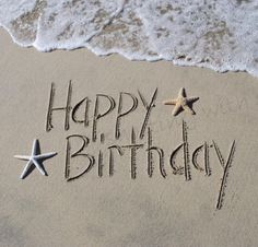 happy birthday written in the sand with starfish