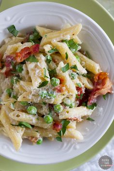 pasta with peas and bacon in a white bowl