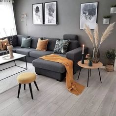 a living room with grey couches and orange throw blankets on the floor, coffee table