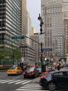 cars are stopped at an intersection in front of tall buildings with skyscrapers on either side