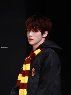 a young man wearing a harry potter scarf and black jacket with his hands in his pockets