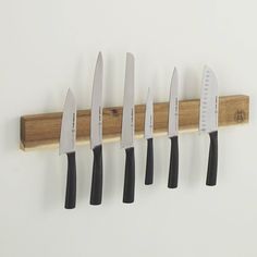 five knives are hanging on a wooden rack