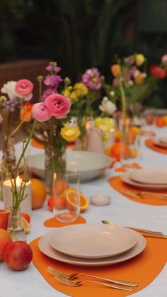 the table is set with plates, silverware and vases filled with colorful flowers