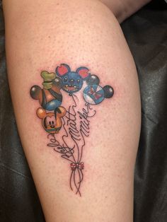 a tattoo on the leg of a woman with mickey mouse balloons and other cartoon characters