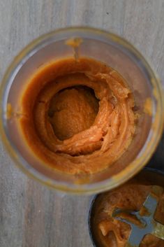 an overhead view of a blender filled with orange colored liquid and peanut butter in it