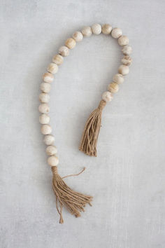 a white beaded necklace with tassels and beads on it's end