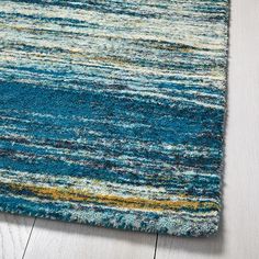 a blue rug with multicolored stripes on the top and bottom, sitting on a wooden floor