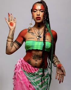 a woman with tattoos on her body and hands in the air, wearing a colorful skirt