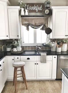 a kitchen with white cabinets and black counter tops, along with a wooden stool in front of the sink