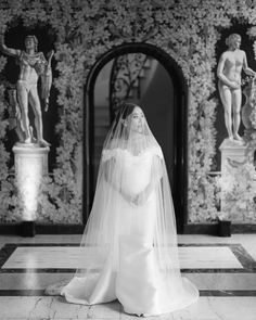 a woman in a wedding dress standing on a tiled floor next to some wallpaper