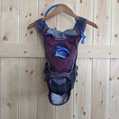 a purple backpack hanging on a wooden wall