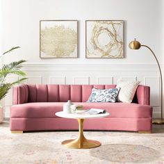 a living room with pink couches and paintings on the wall above it, along with a coffee table