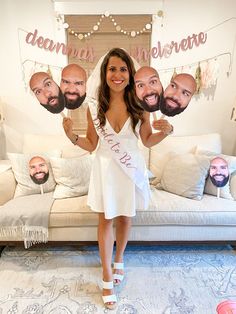 a woman standing in front of a couch holding up two cutouts of people's heads