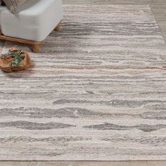 an area rug with grey and white stripes on the floor in front of a couch