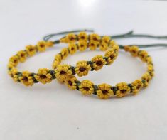 three yellow and green crocheted bracelets with flowers on them sitting on a white surface