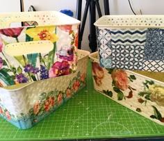 two flowered containers sitting on top of a green cutting board next to each other