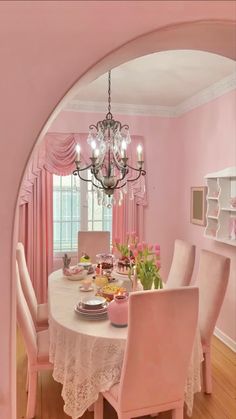 pink dining room with chandelier and table set for four in front of window