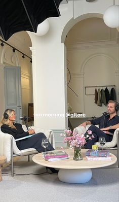 a man and woman sitting in chairs talking to each other