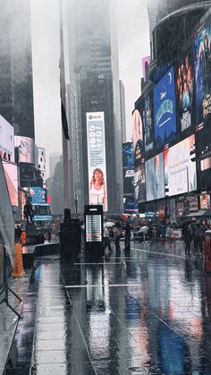 people walking in the rain with umbrellas and billboards behind them on a city street