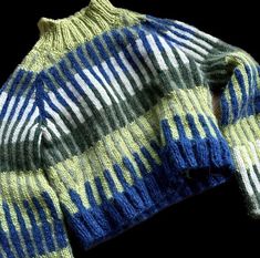 a blue and yellow sweater is shown on a black background, with the top half folded up