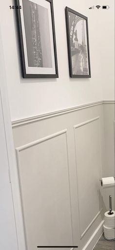 a white toilet sitting in a bathroom next to a wall with pictures on the walls