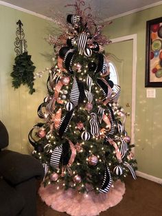 a decorated christmas tree with black and white ribbons on it in a living room area