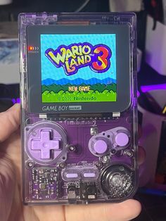 a person holding up a gameboy in their left hand and playing mario land 3 on the screen