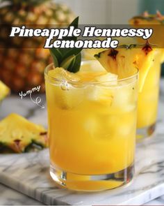 pineapple hennessy lemonade in a glass on a marble table with pineapples behind it