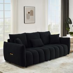 a black couch sitting on top of a rug in a living room next to a window