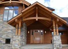 the front entrance to a house with stone pillars and wood trimmings on it