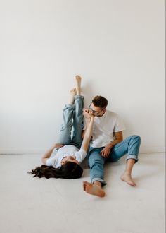 two people laying on the ground with their feet up and one person touching his face